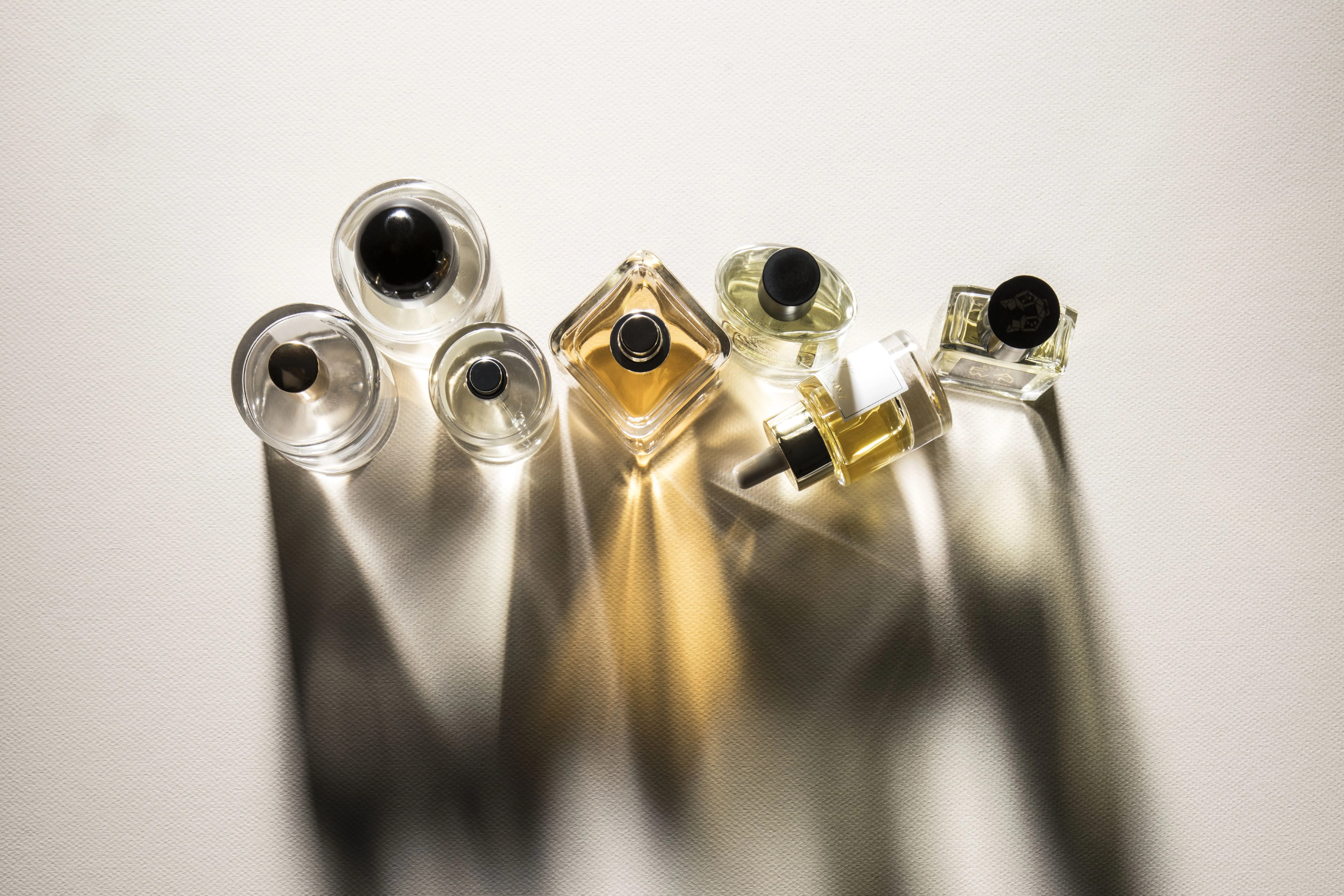 Frascos de perfume iluminados por luz natural sobre tecido claro